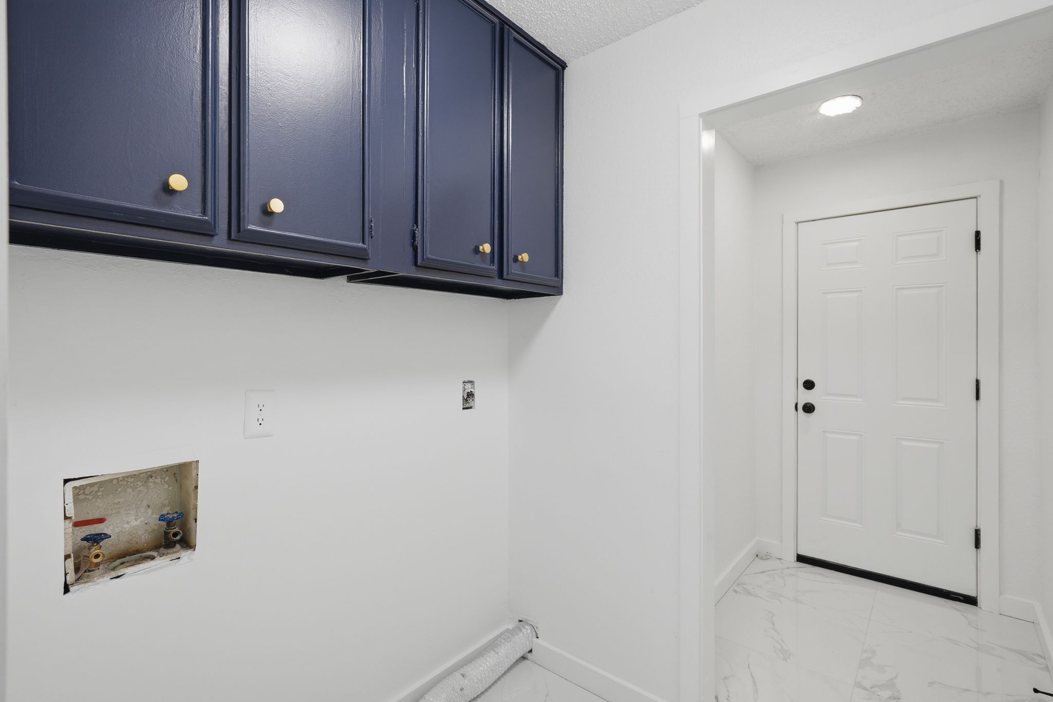 6804 Meadow Run Austin, TX 78745 - Photo 29 of 34 Laundry area featuring blue wall-mounted cabinetry with brass hardware, white walls, and white flooring