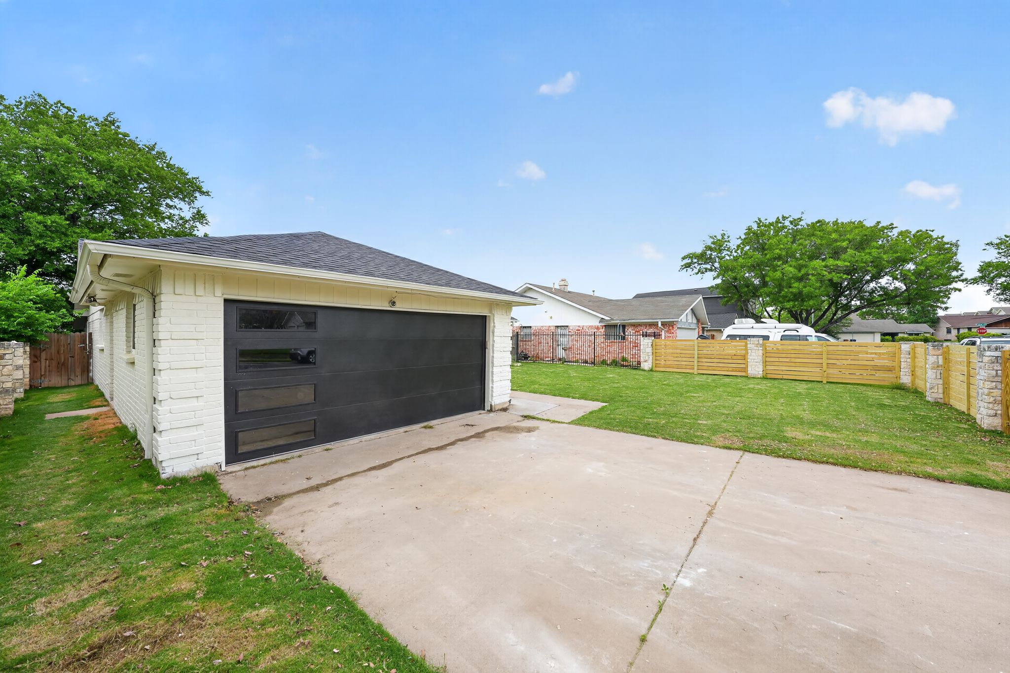 6804 Meadow Run Austin, TX 78745 - Photo 5 of 34 Detached garage with a dark-colored door featuring rectangular windows, set against a white brick exterior