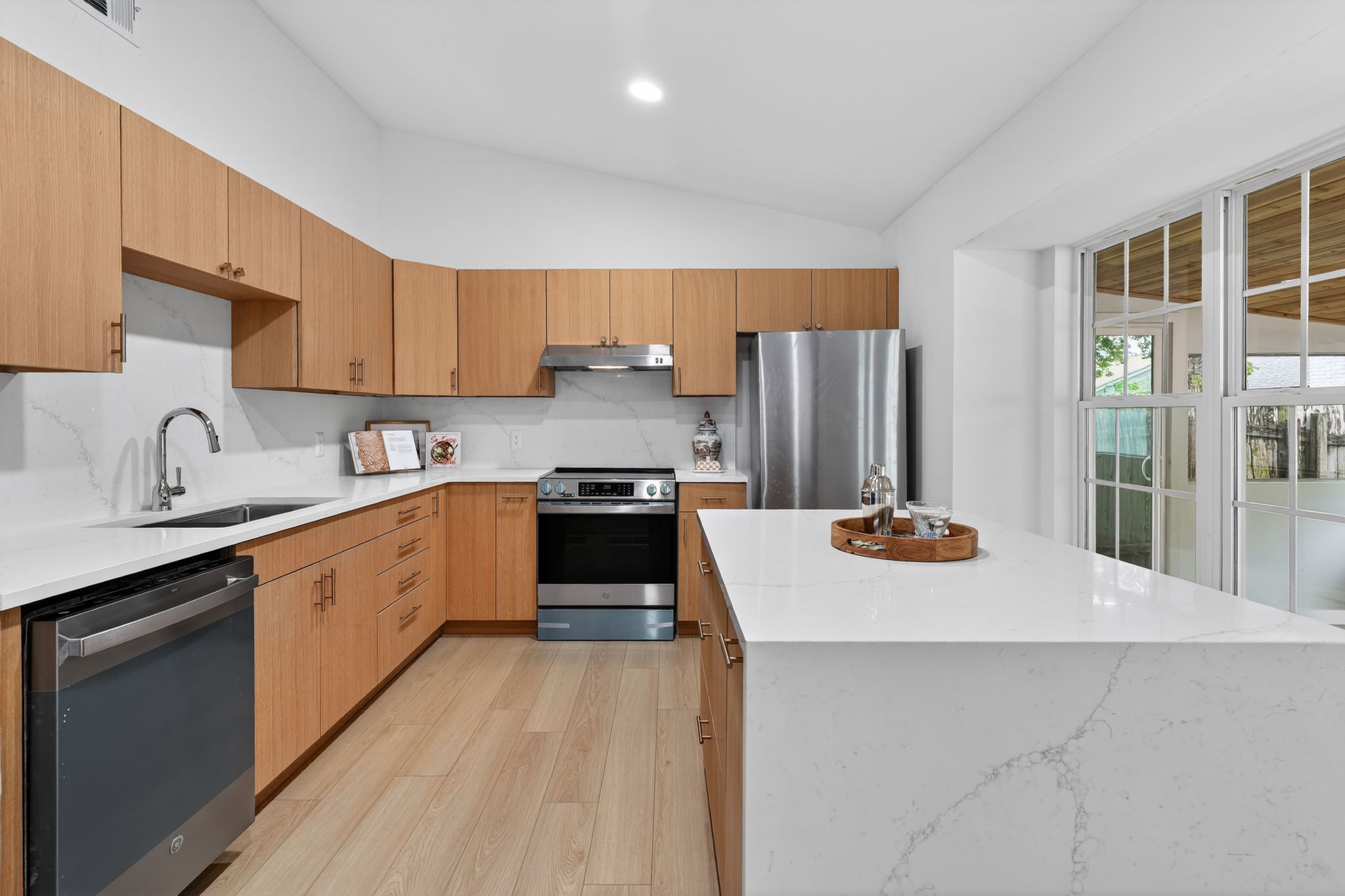 6804 Meadow Run Austin, TX 78745 - Photo 8 of 34 The kitchen features light wood cabinetry, stainless steel appliances, a white countertop with a waterfall edge, and light wood flooring