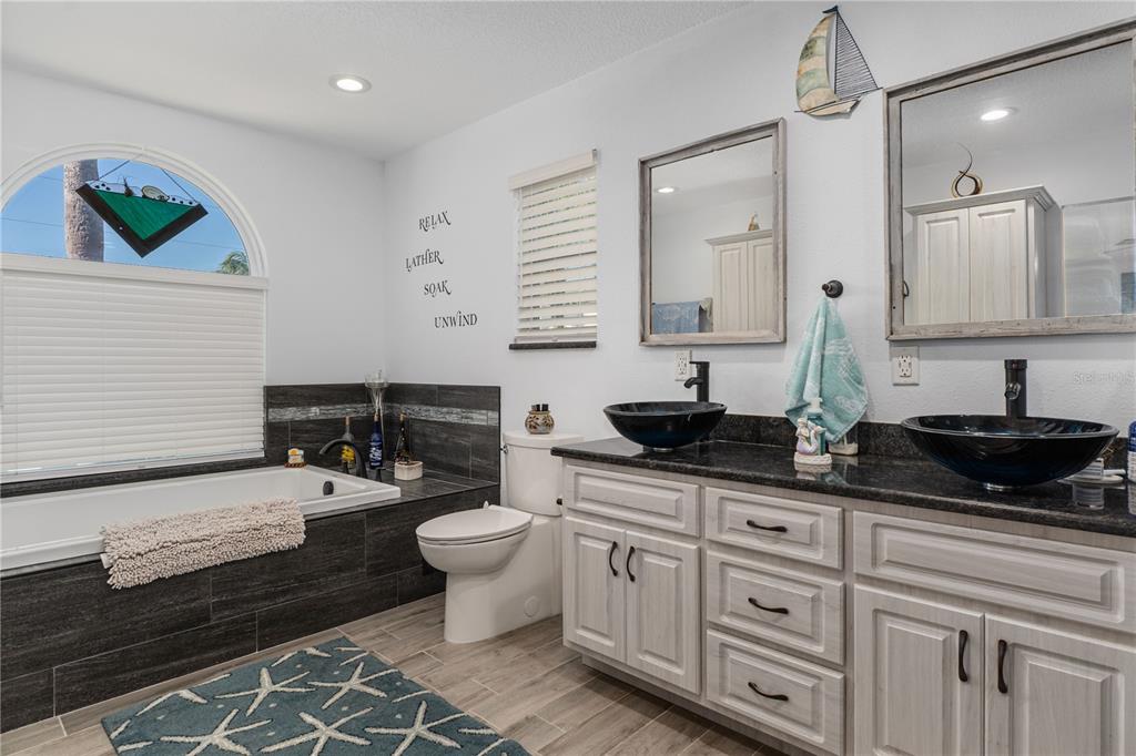 4128 Camelia Drive Hernando Beach, FL 34607 - Photo 29 of 50 a bathroom with a double vanity sink a mirror and a bathtub