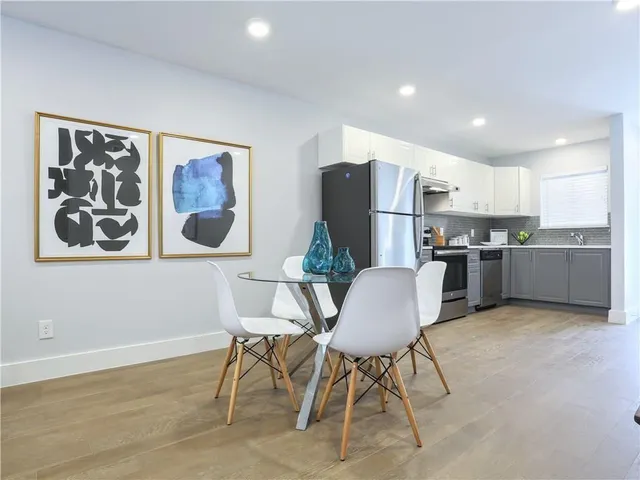 a living room with stainless steel appliances furniture a dining table and kitchen view