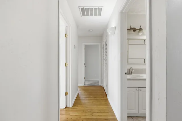 a view of a hallway with wooden floor and closet