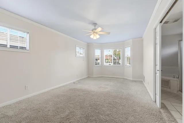 an empty room with windows and ceiling fan