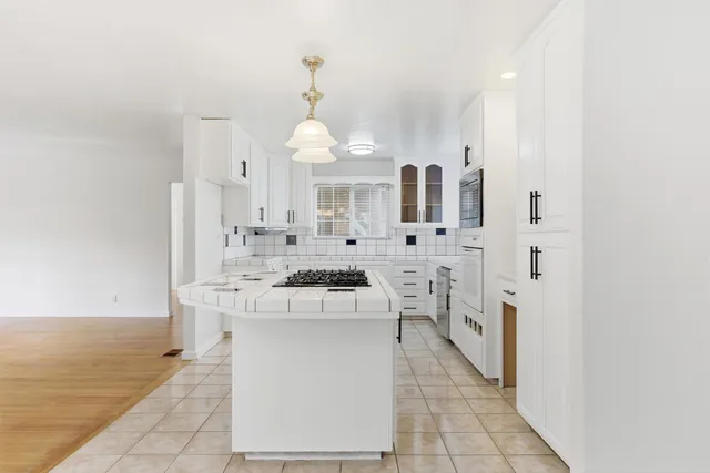 a large white kitchen with a stove a sink dishwasher and a refrigerator with wooden floor