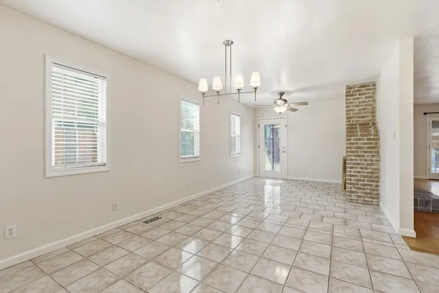 a view of an empty room with window and chandelier fan