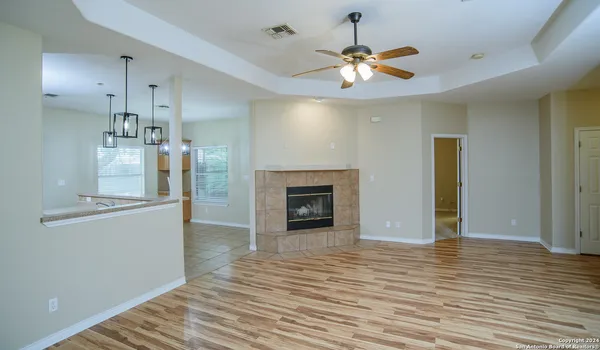 a view of a livingroom with a fireplace a chandelier fan and wooden floor