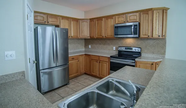 a kitchen with stainless steel appliances granite countertop a refrigerator stove top oven and sink