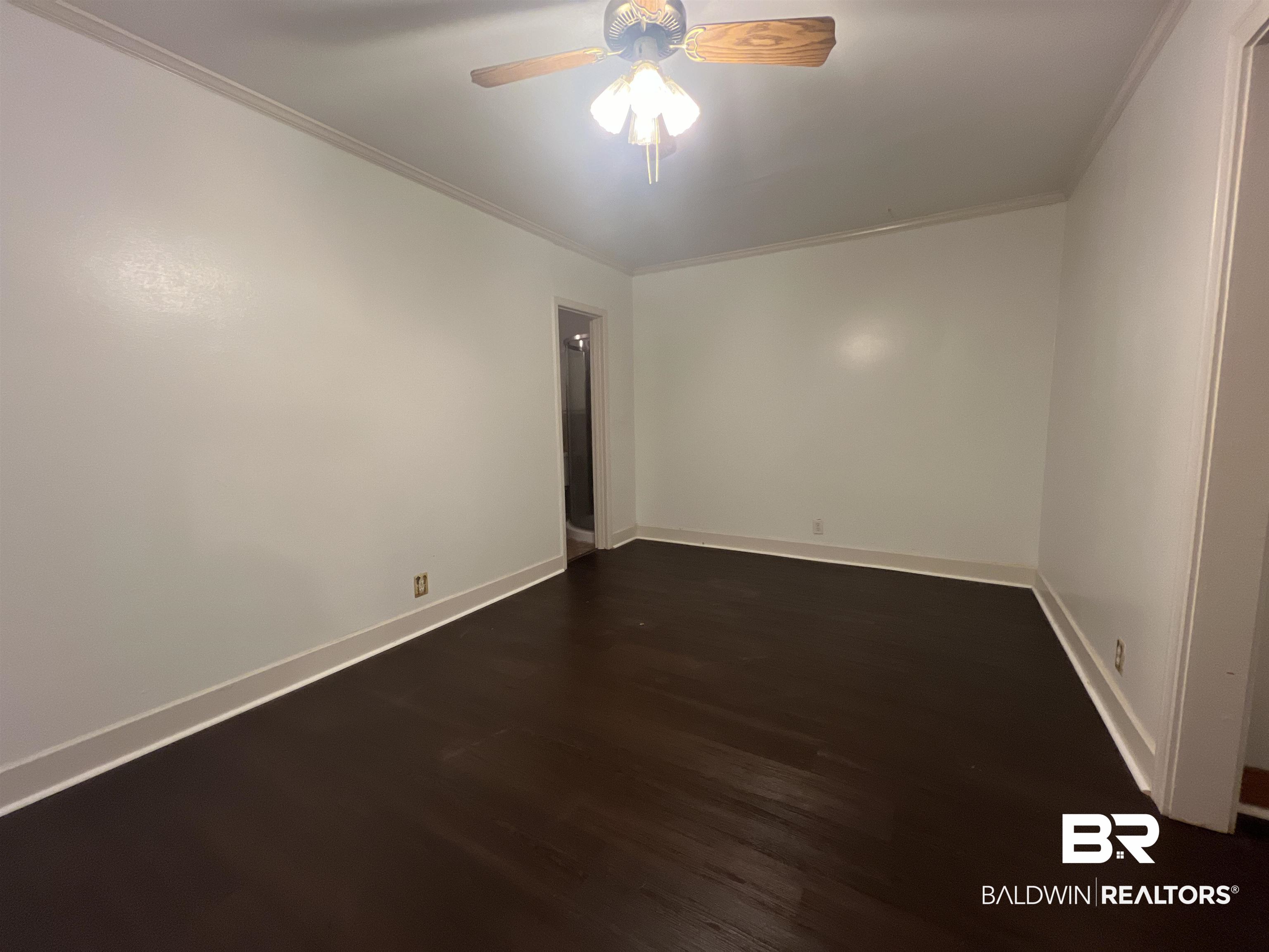 13301 A Hugh Fort Road Grand Bay, AL 36541 - Photo 13 of 34 Unfurnished room with crown molding, a ceiling fan, dark wood finished floors, and baseboards