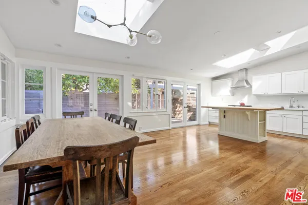 a living room with stainless steel appliances granite countertop a dining table chairs and wooden floor
