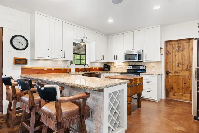 a kitchen with stainless steel appliances granite countertop a stove a sink and a refrigerator