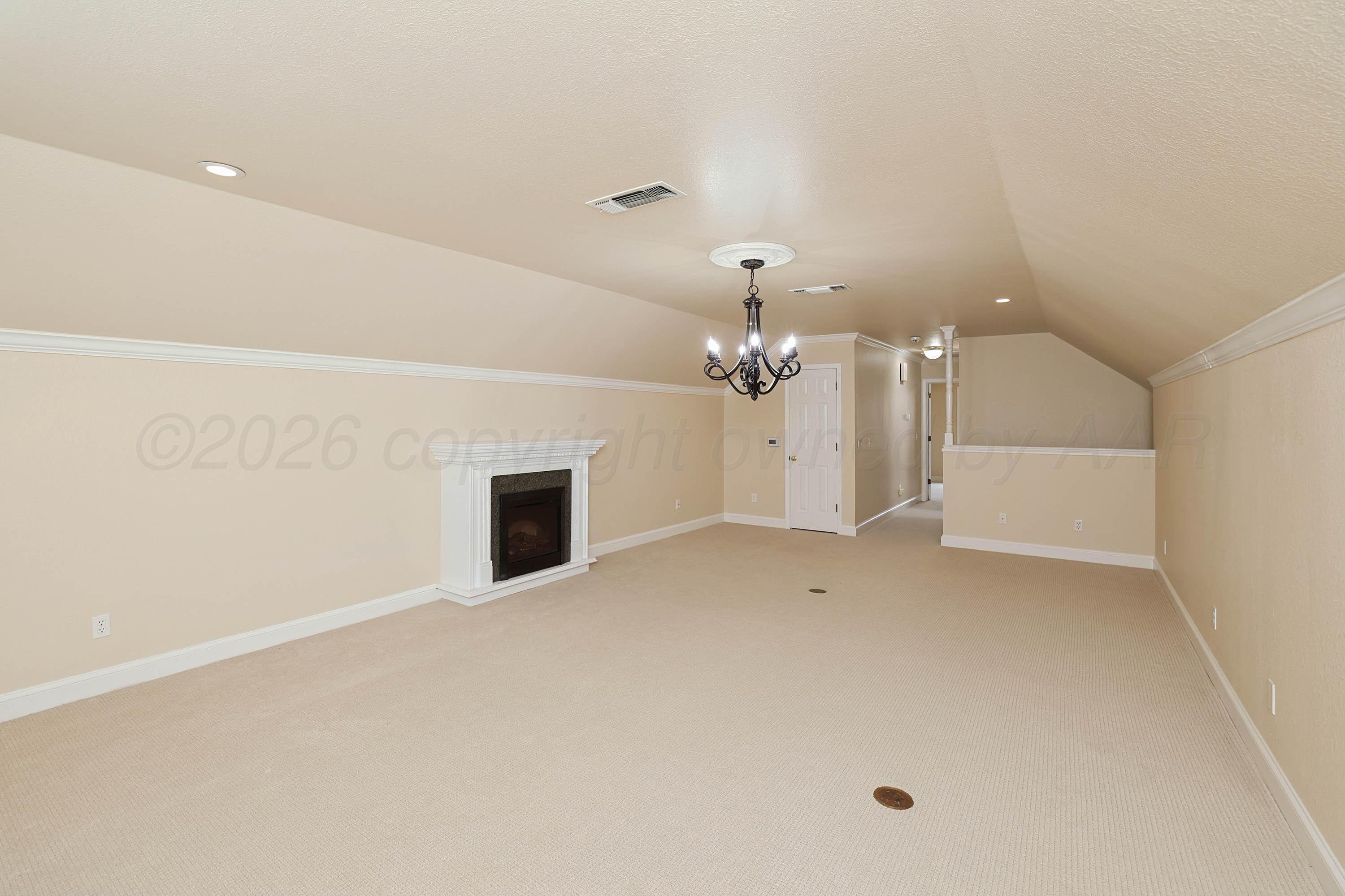 6904 Alpine Lane Amarillo, TX 79109 - Photo 27 of 45 an empty room with a fireplace and chandelier fan