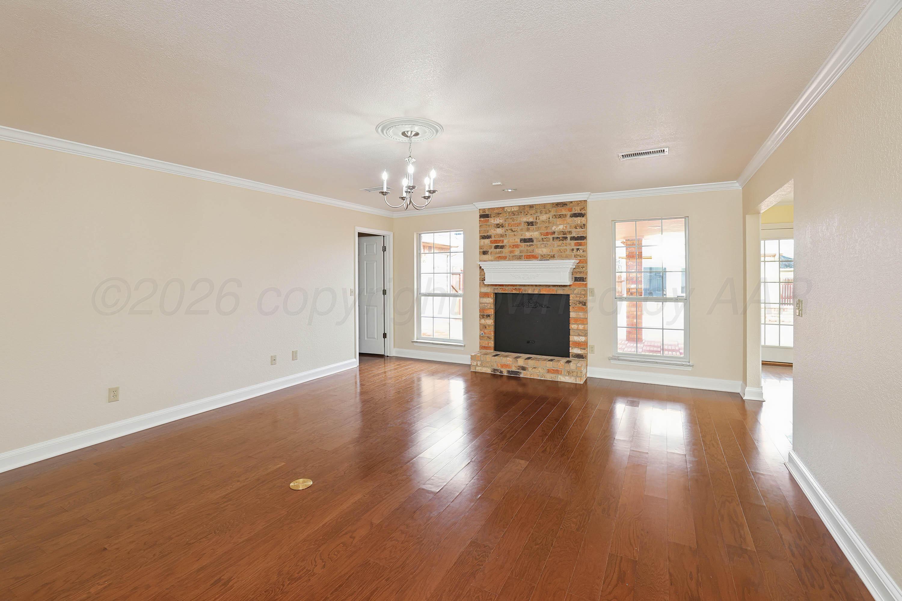 6904 Alpine Lane Amarillo, TX 79109 - Photo 4 of 45 an empty room with wooden floor and fireplace