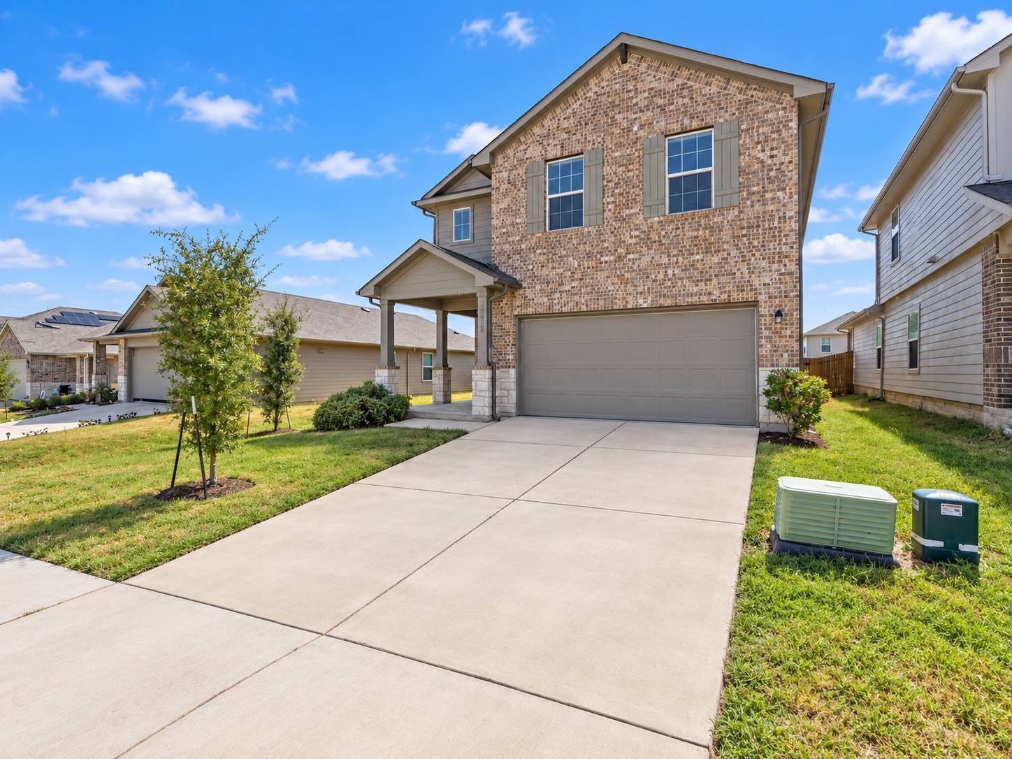 15011 Tuff Rd Manor Manor, TX 78653 - Photo 5 of 37 Brick and stone exterior with shuttered windows, a two-car garage, and curb appeal in a well-kept residential neighborhood.