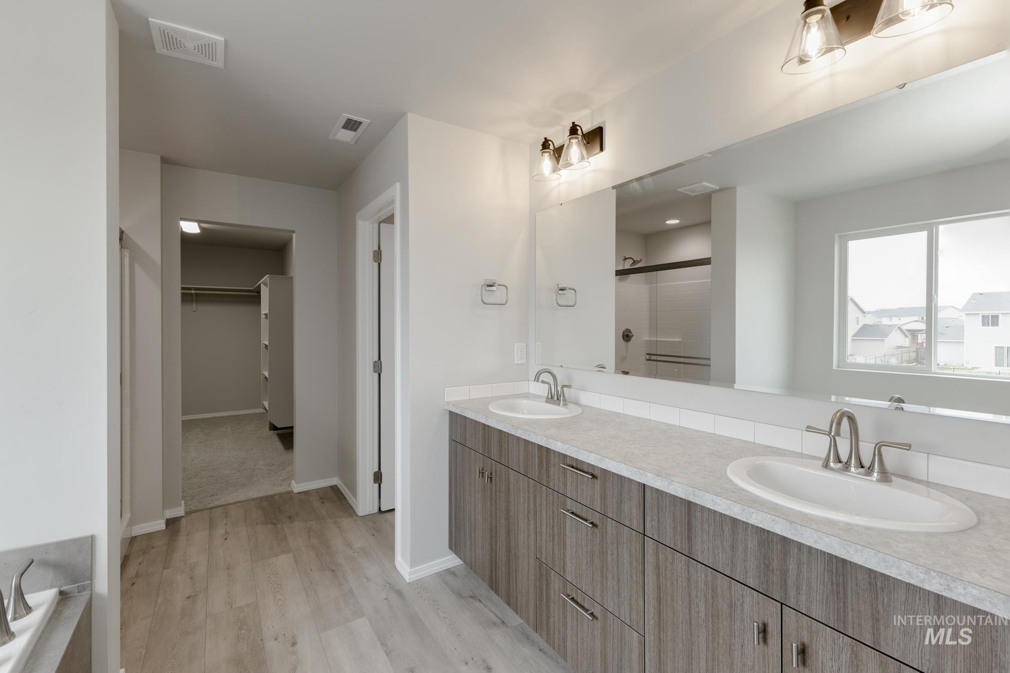 12842 Ropers Street Nampa, ID 83651 - Photo 26 of 29 Spacious bathroom featuring a dual vanity with wood-finish cabinetry, light-toned countertops, and two undermount sinks with brushed nickel fixtures