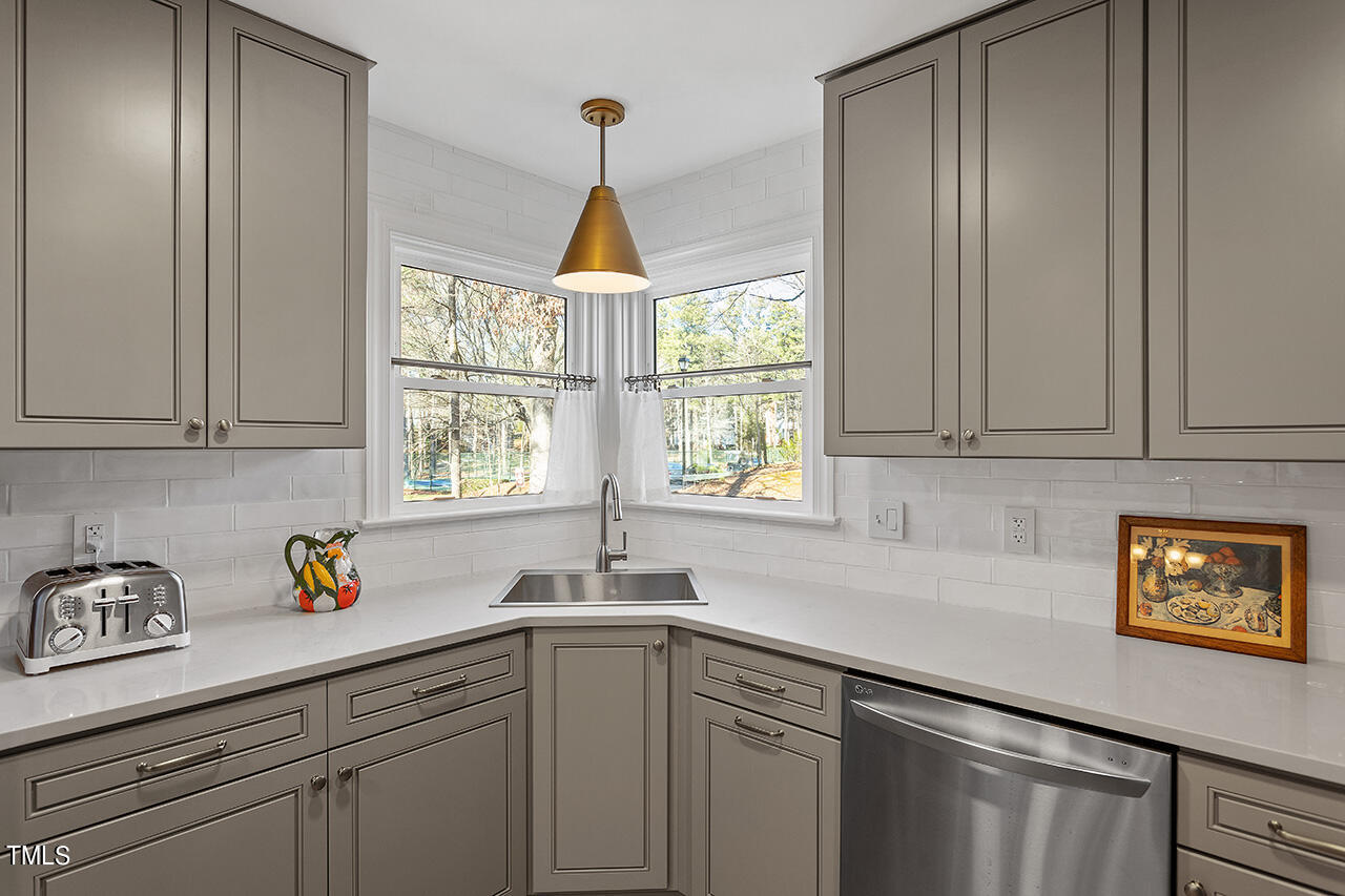 6933 Sandringham Drive Raleigh, NC 27613 - Photo 12 of 30 a kitchen with stainless steel appliances granite countertop a sink a window and cabinets
