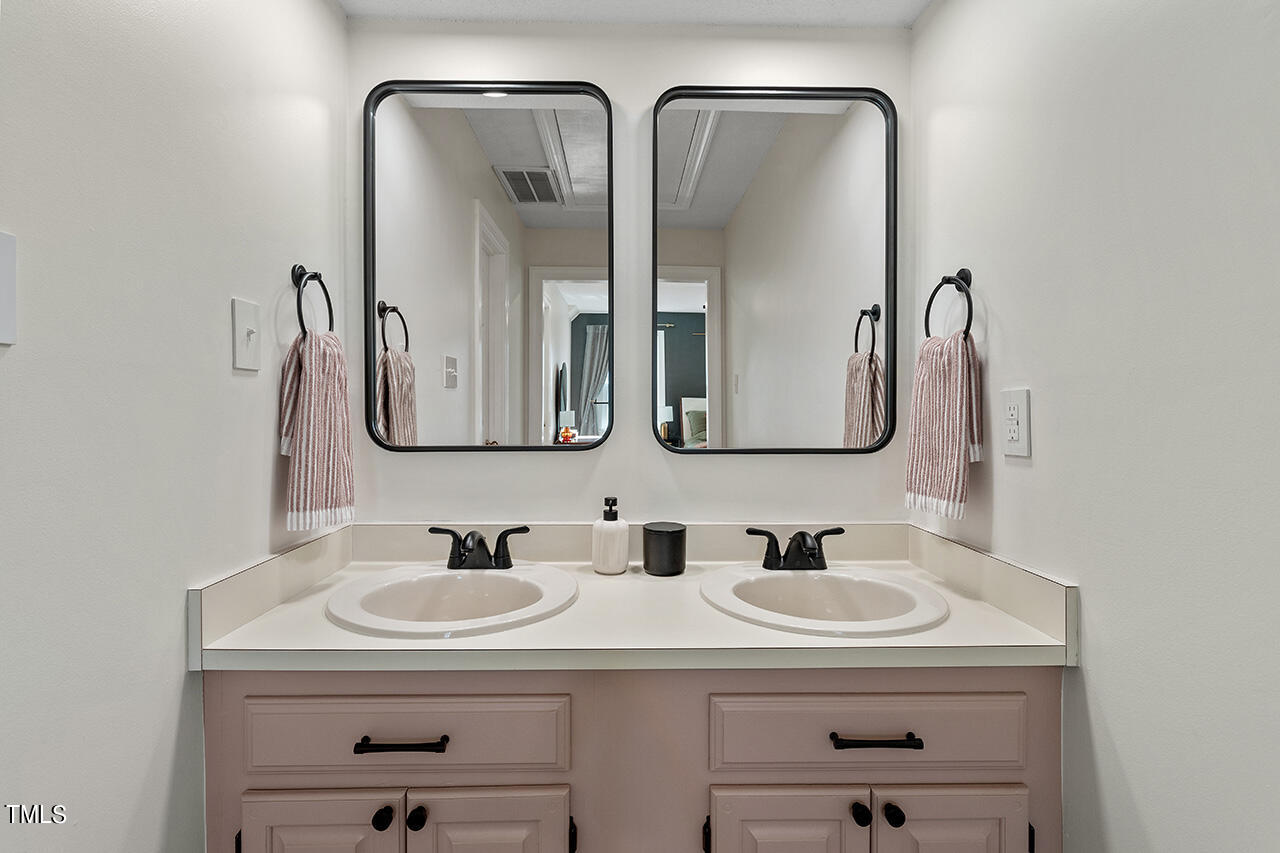 6933 Sandringham Drive Raleigh, NC 27613 - Photo 19 of 30 a bathroom with double vanity sinks and a mirror