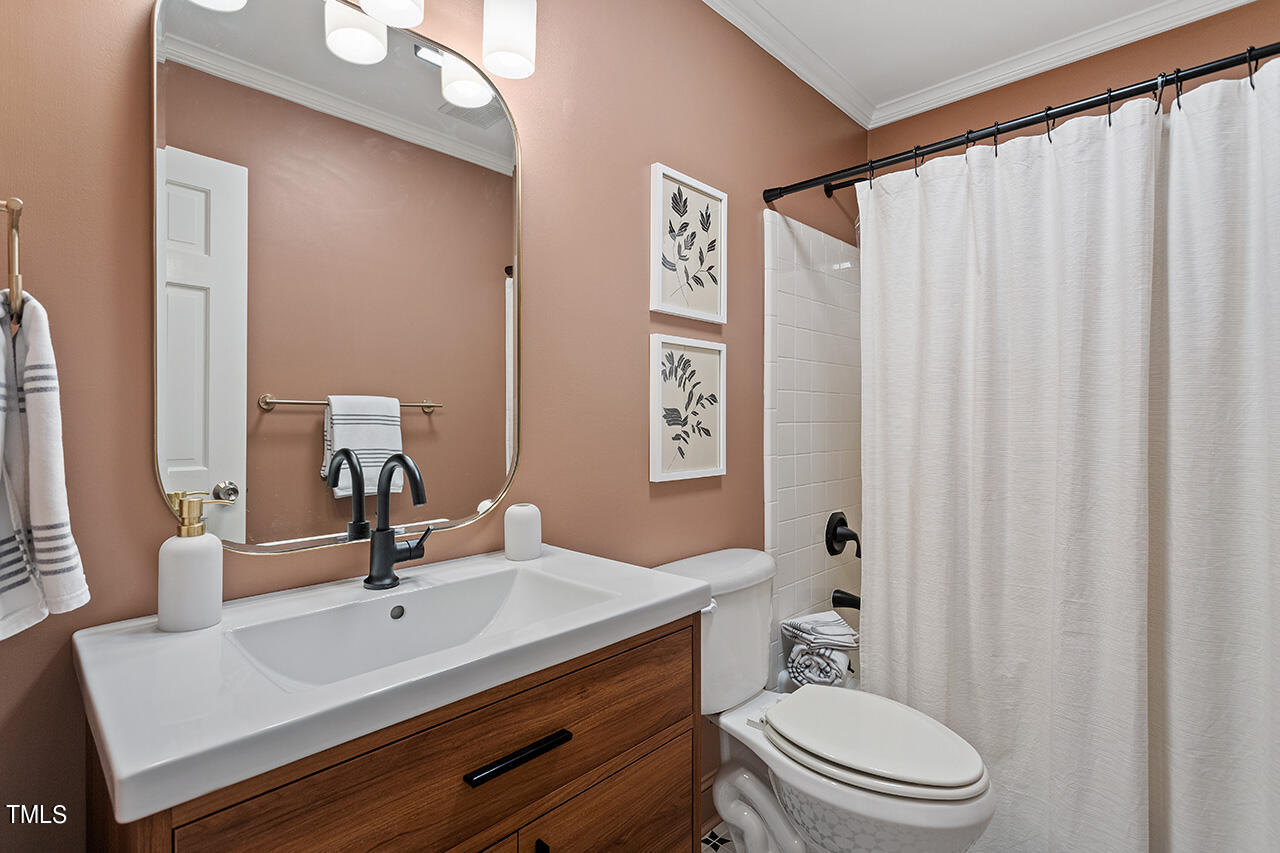 6933 Sandringham Drive Raleigh, NC 27613 - Photo 21 of 30 a bathroom with a sink a toilet and shower curtain
