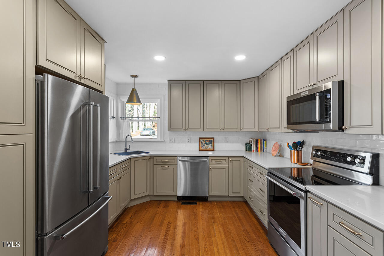6933 Sandringham Drive Raleigh, NC 27613 - Photo 10 of 30 a kitchen with stainless steel appliances granite countertop refrigerator a sink a stove top oven and wooden floors