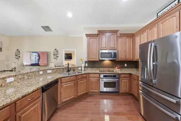 a kitchen with stainless steel appliances granite countertop a sink stove refrigerator and cabinets