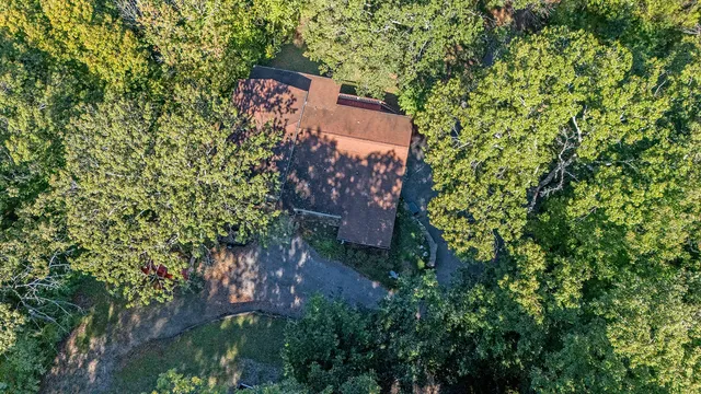 an aerial view of a house with a yard and covered with trees