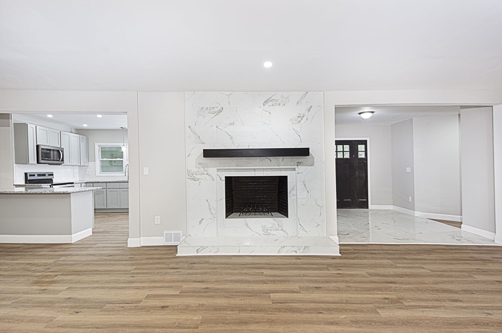 32 Aylesbury Road Worcester, MA 01609 - Photo 13 of 42 a view of a living room kitchen with a fireplace and wooden floor
