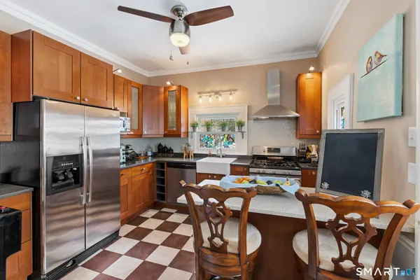 a kitchen with stainless steel appliances granite countertop a refrigerator a stove a sink a dining table and chairs with wooden floor