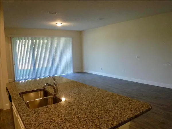 a view of kitchen island a sink wooden floor and glass door