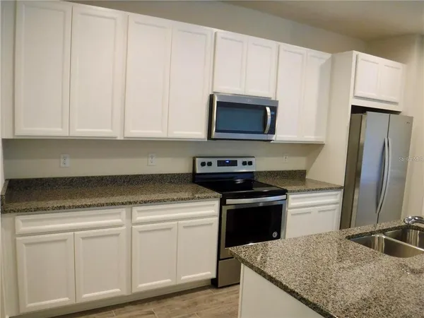 a kitchen with granite countertop white cabinets and stainless steel appliances