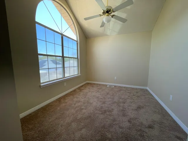 an empty room with windows and fan