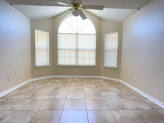 an empty room with windows and chandelier fan