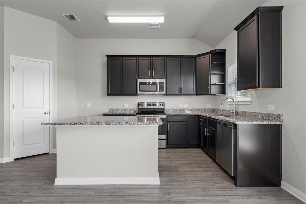 3921 Centerfire Road Waco, TX 76705 - Photo 9 of 16 a kitchen with stainless steel appliances granite countertop a stove a sink and a microwave