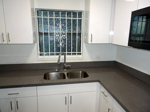 a kitchen with granite countertop a sink and white cabinets