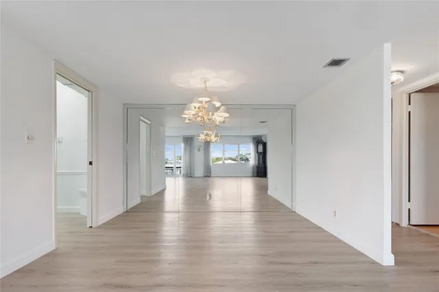 a view of a hallway with wooden floor and a kitchen