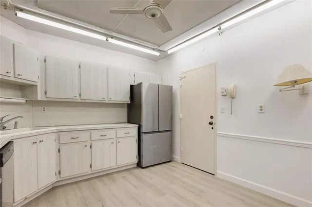 a kitchen with white cabinets and refrigerator