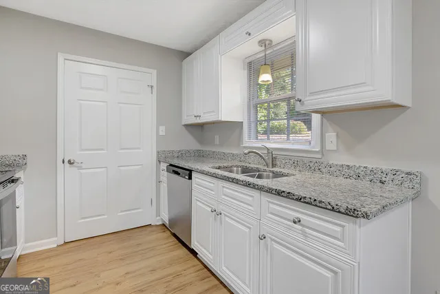 a kitchen with granite countertop white cabinets and a sink