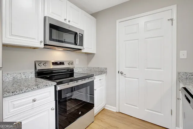 a kitchen with stainless steel appliances granite countertop white cabinets and a stove top oven