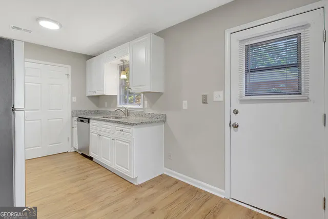 a kitchen with granite countertop white cabinets and white appliances