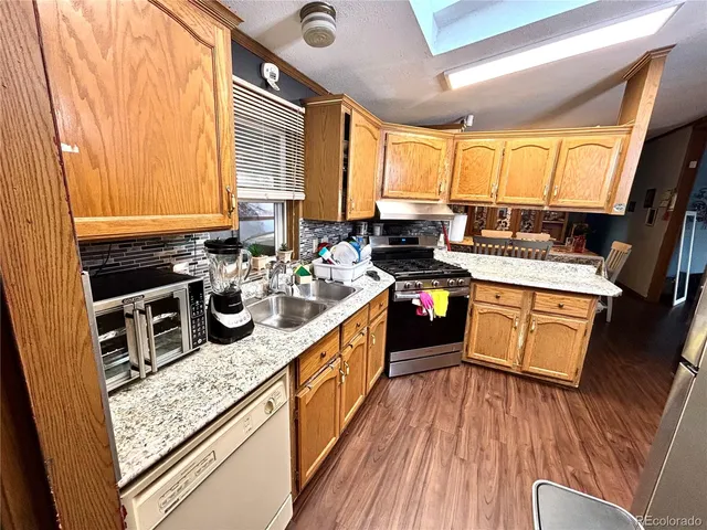 a kitchen with stainless steel appliances granite countertop a stove a sink dishwasher and wooden cabinets with wooden floor