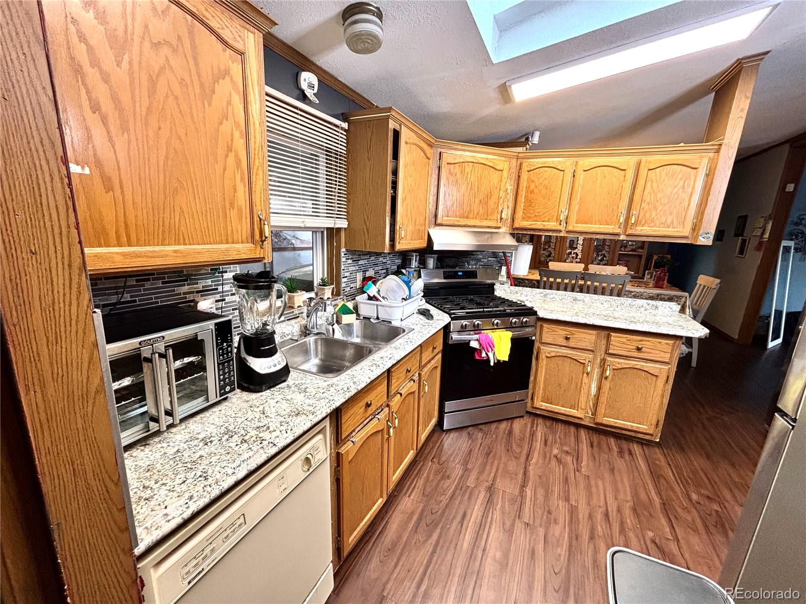 2660 Hawk Street Denver, CO 80260 - Photo 10 of 25 a kitchen with stainless steel appliances granite countertop a stove a sink dishwasher and wooden cabinets with wooden floor