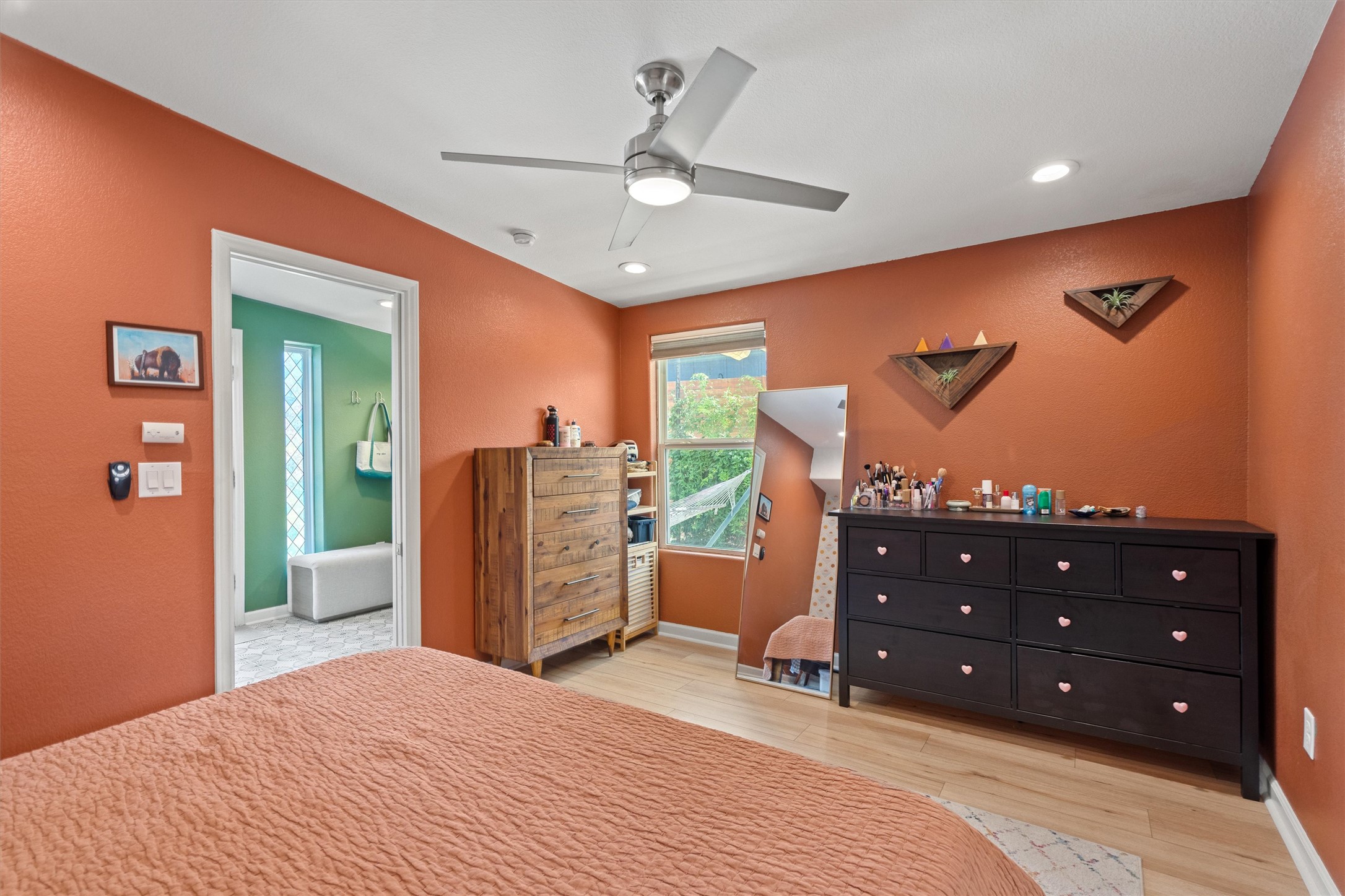 1147 Webberville Road Austin, TX 78721 - Photo 22 of 37 Natural light illuminates a cozy bedroom featuring wood flooring and a modern ceiling fan.