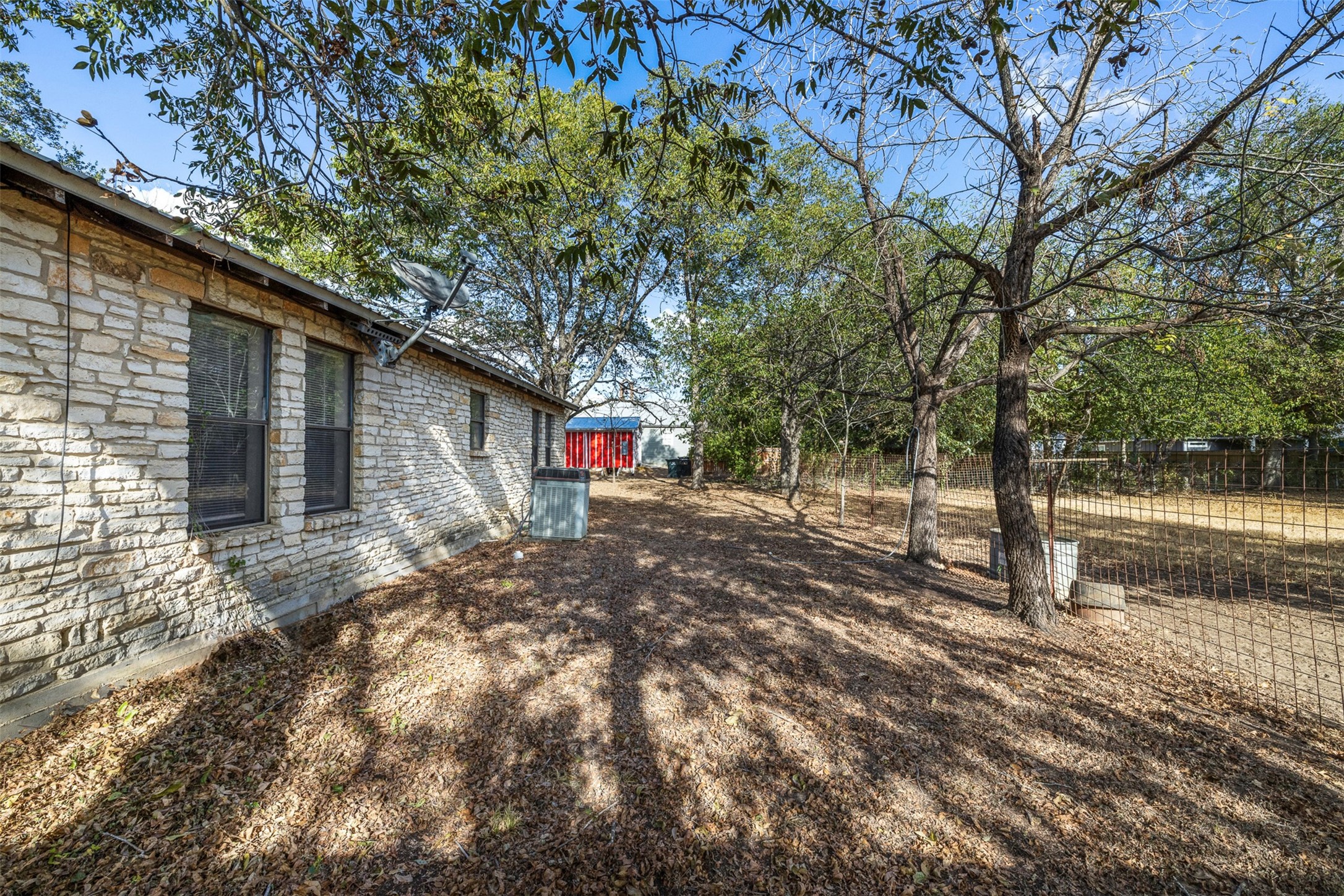 517 First Street Lexington, TX 78947 - Photo 16 of 37 a backyard of a house with large trees and a wooden fence
