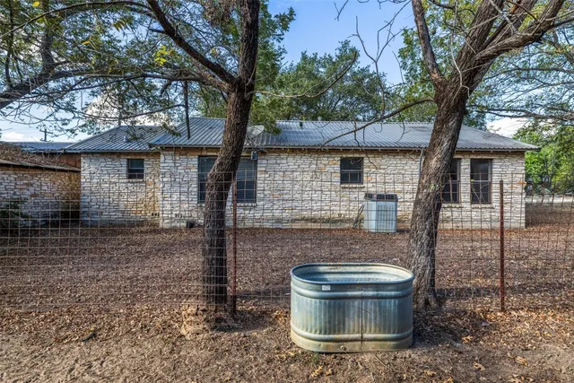 a backyard of a house with table and chairs plants and large trees