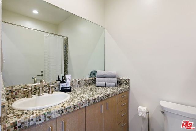 a bathroom with a granite countertop sink and a mirror with toilet