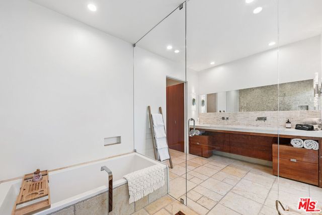 a large bathroom with a tub sink and mirror