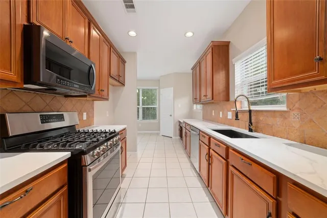 a kitchen with stainless steel appliances kitchen island granite countertop a sink a stove top oven a counter space and cabinets