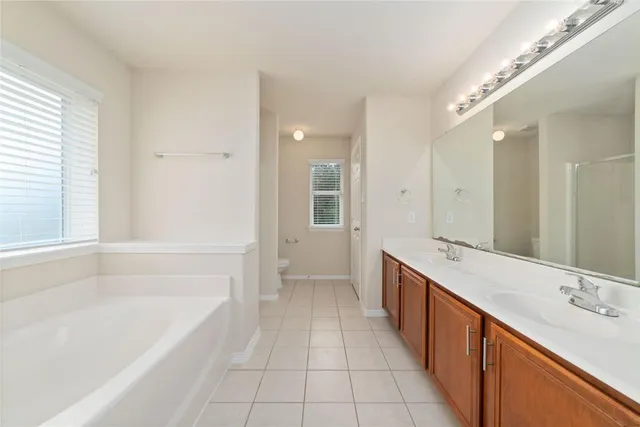 a spacious bathroom with a tub sink shower and mirror