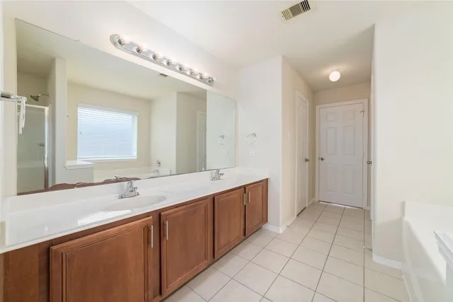 a spacious bathroom with a double vanity sink mirror and bathtub