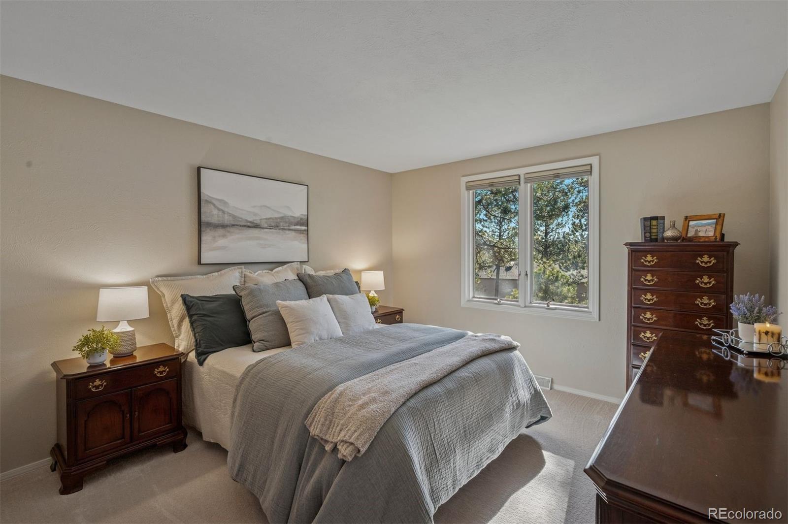 32329 Inverness Drive Evergreen, CO 80439 - Photo 30 of 48 a bedroom with a bed and a flat tv screen on a dresser