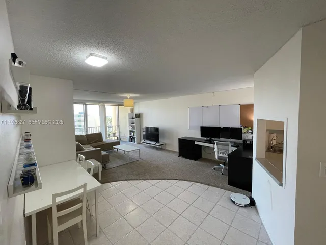 a large living room with stainless steel appliances furniture a flat screen tv and a refrigerator