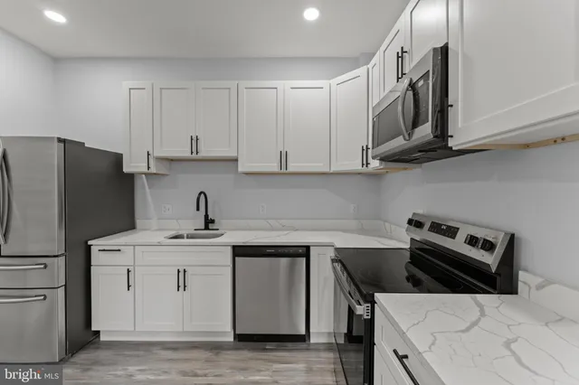 a kitchen with granite countertop white cabinets and stainless steel appliances